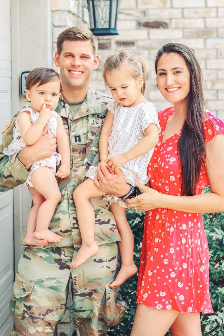 mom and dad holding their two daughters