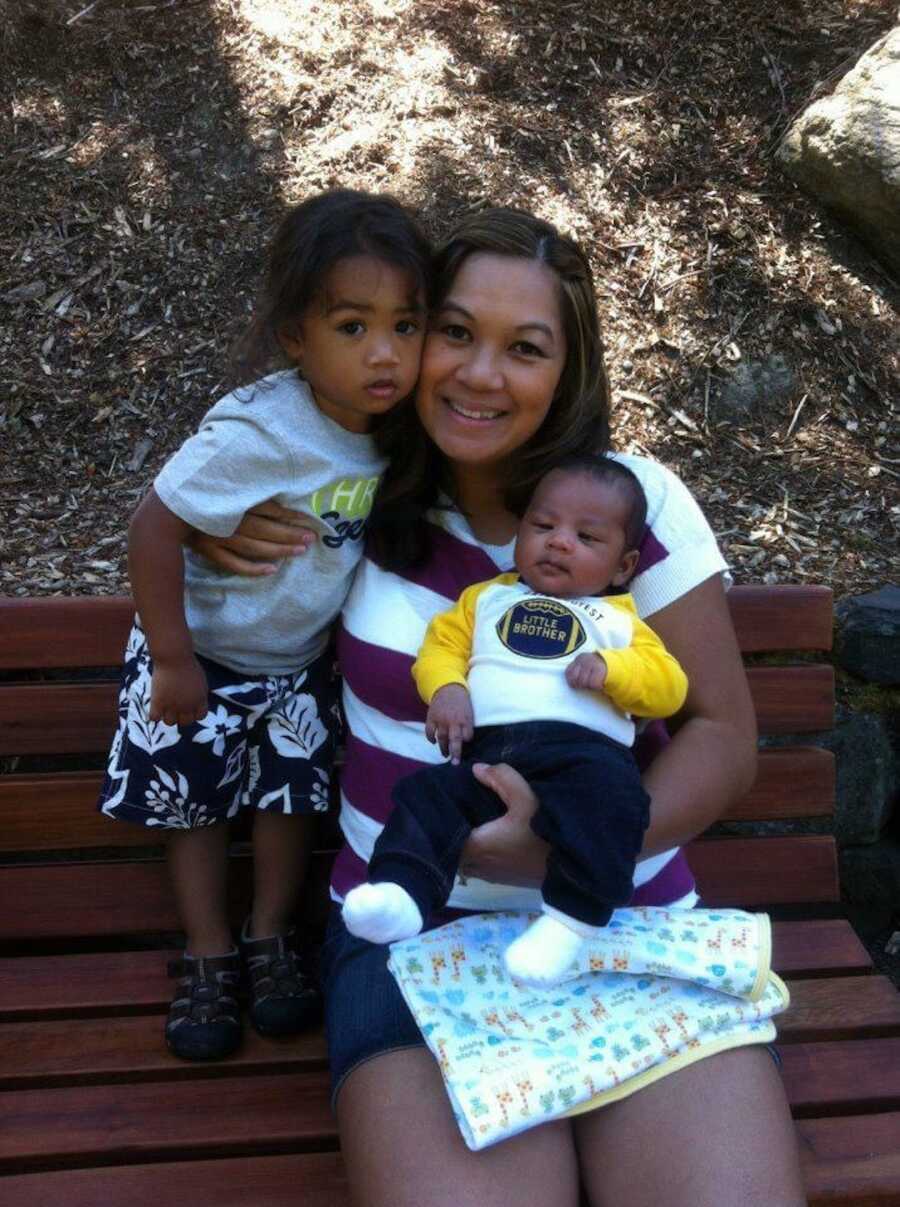 mom holding two sons on bench 