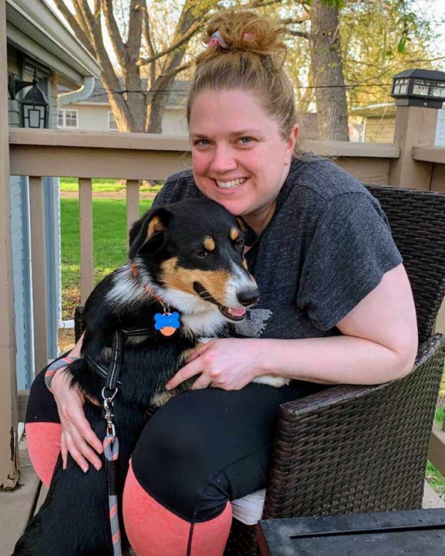 mother sitting with family dog on porch