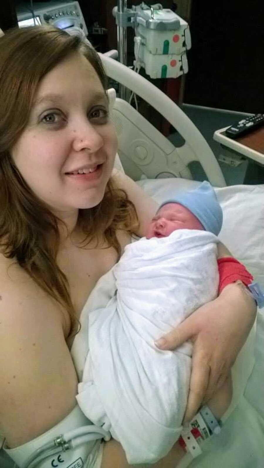 PCOS warrior holding newborn son in hospital bed