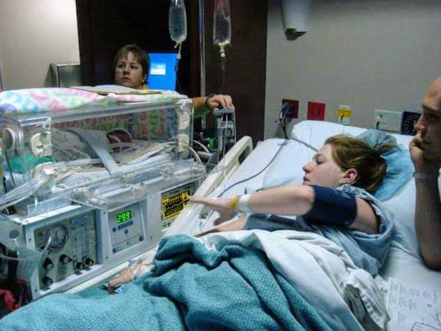 mother in a hospital bed with her baby in a life support box next to her