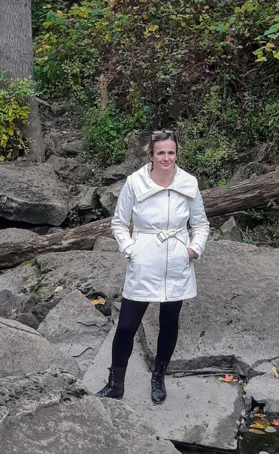 mother wearing a white coat while hiking on rocks on forest