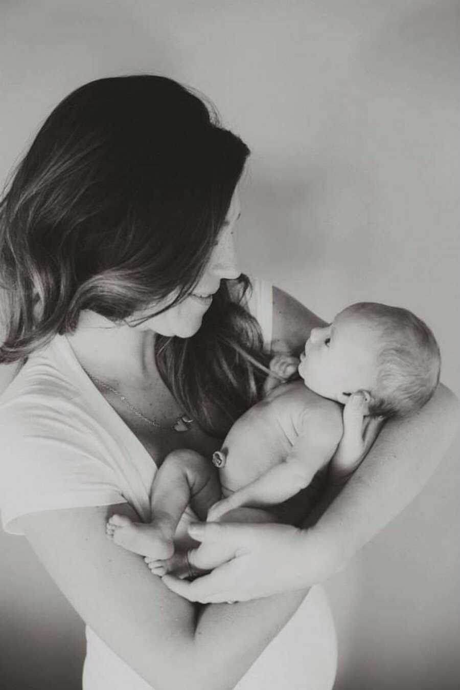 Black and white photo of mother smiling while cradling her baby