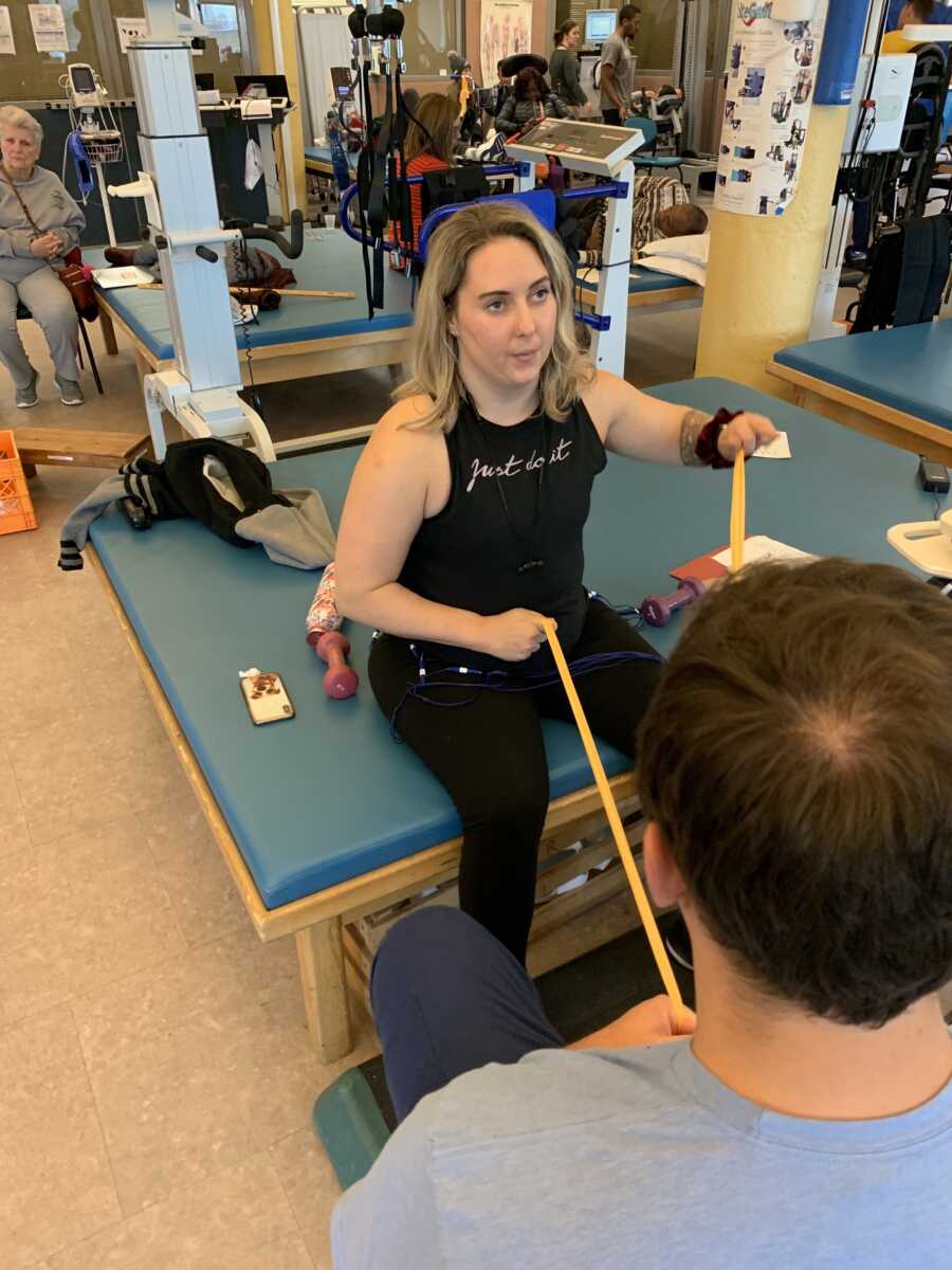 Paralyzed woman sits with therabands in physical training