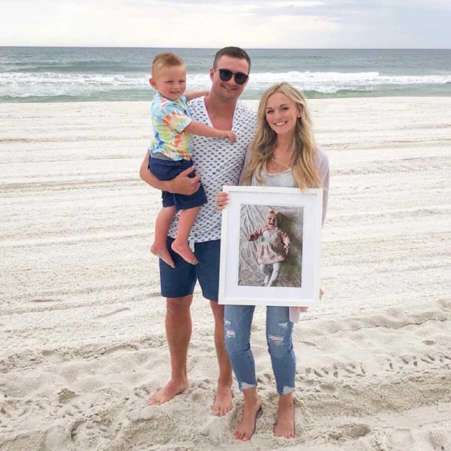 bereaved parents on the beach holding their son, photo of daughter