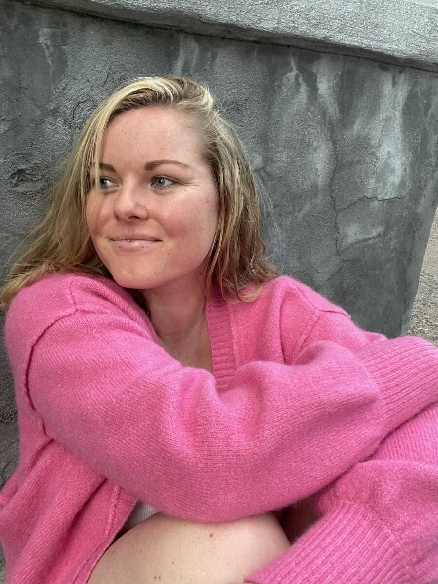 Period educator sits in pink sweater