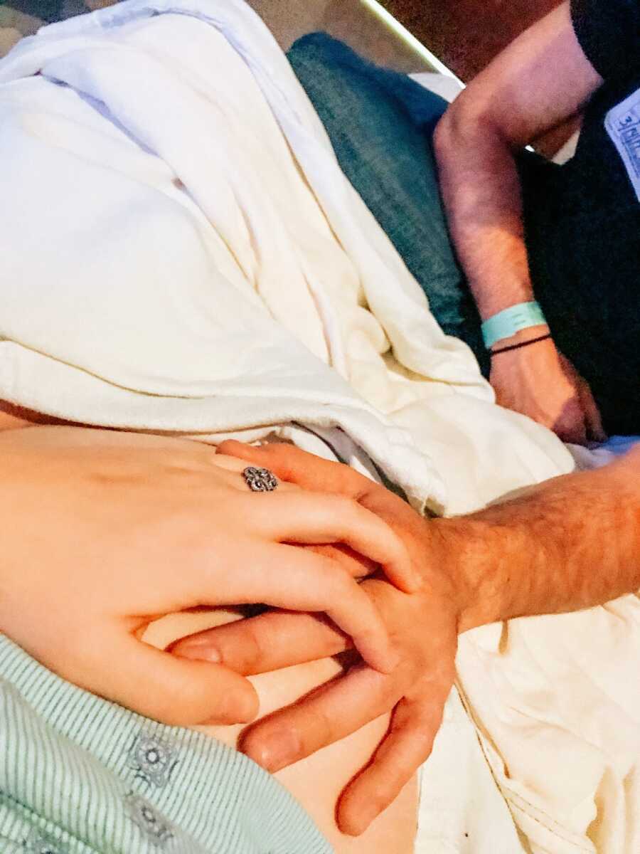 pregnant wife and her husband holding hands on her belly