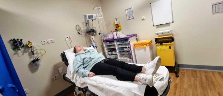 pregnant woman lying in a hospital bed in day clothes