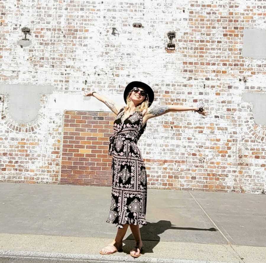 formerly abused mother in a patterned dress by a brick wall