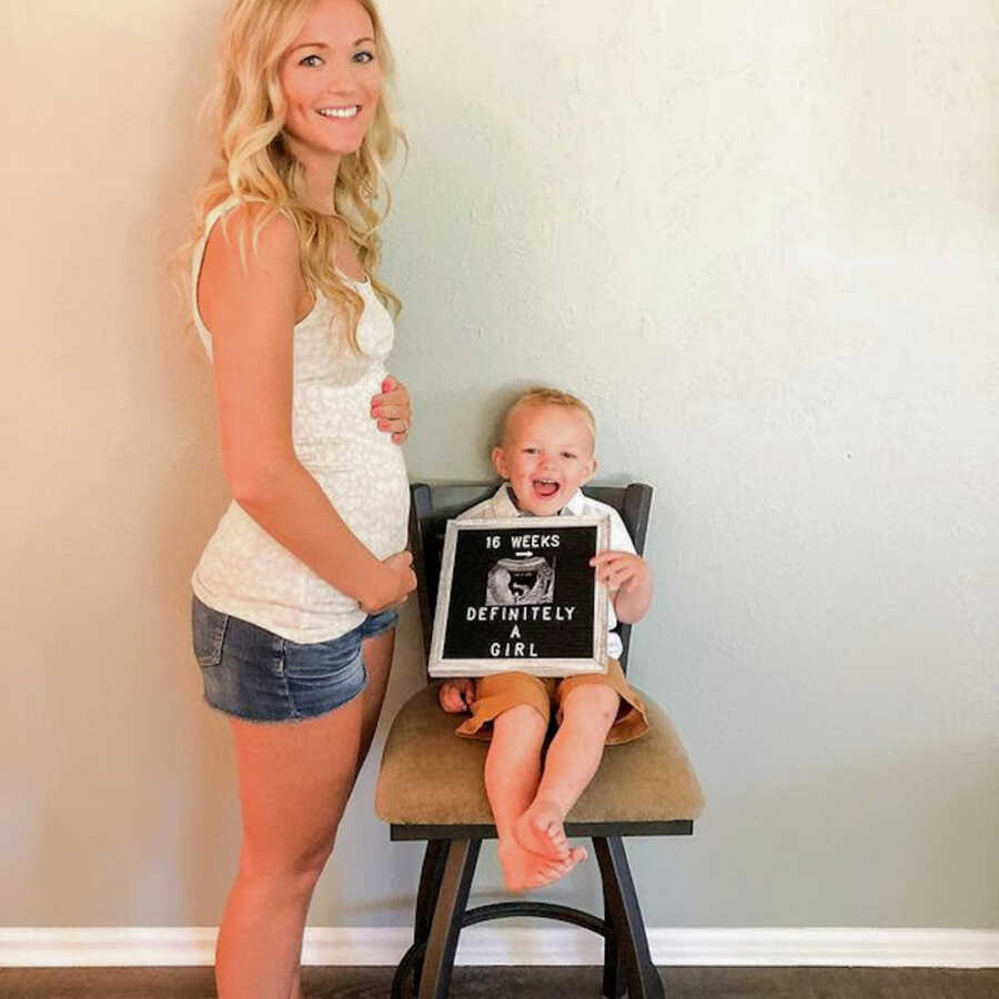 pregnant woman with her son holding a sign saying sixteen weeks