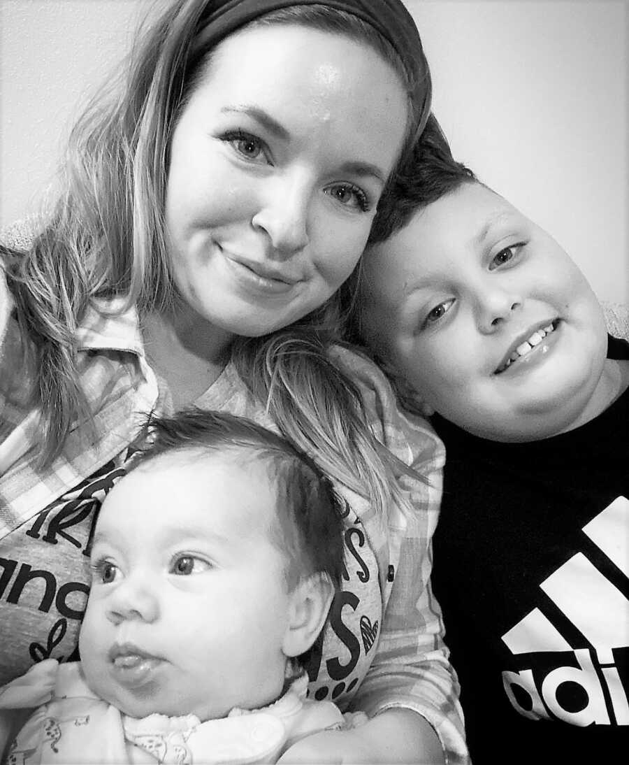 Black and white selfie of mom with her toddler daughter and her young son 