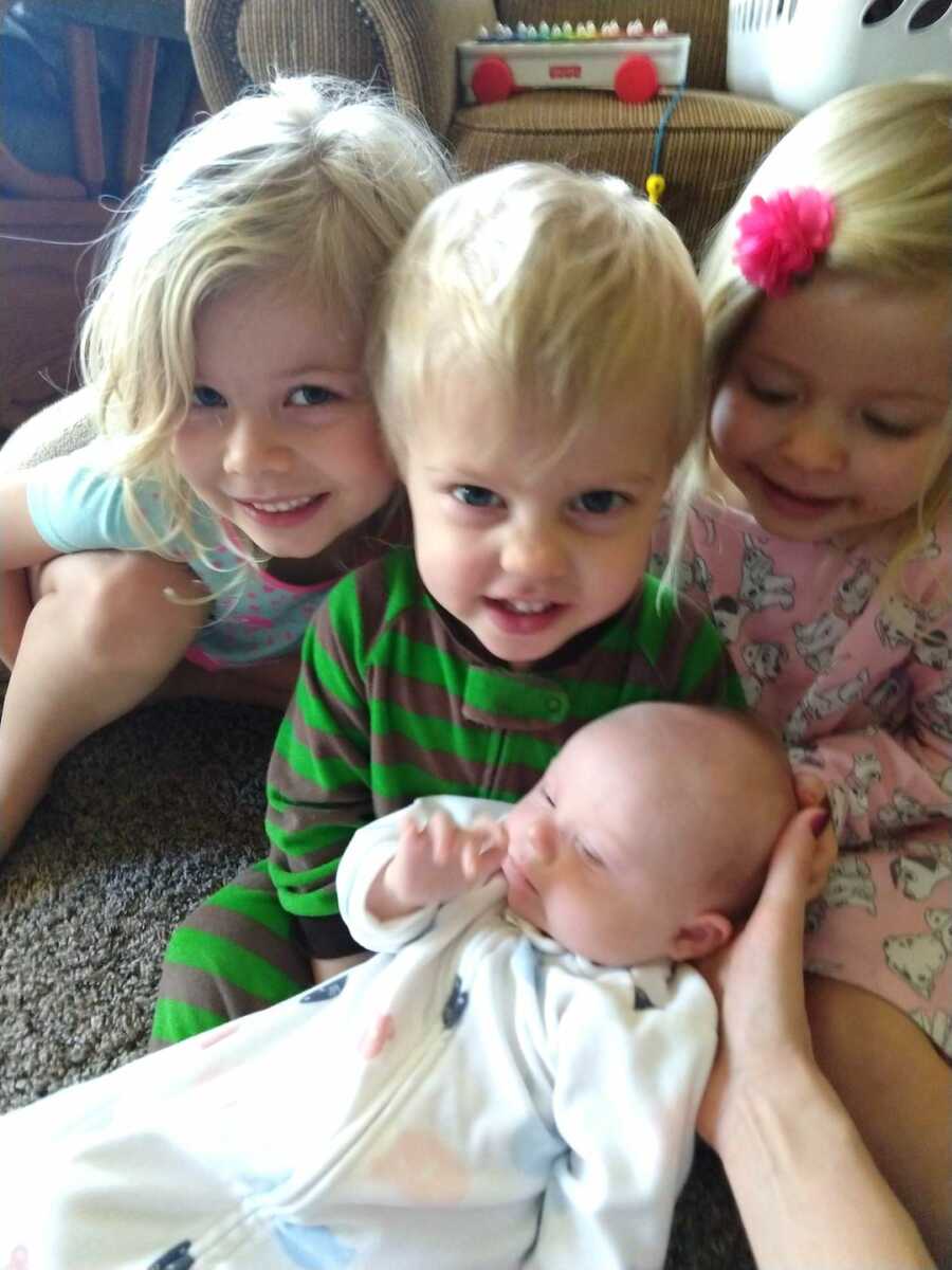 siblings sitting with adopted baby brother