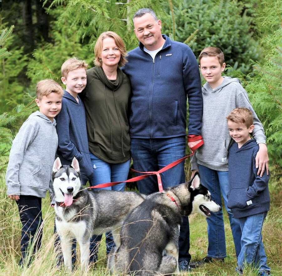 Family portrait of mom and dad outdoors with their 4 sons and two dogs