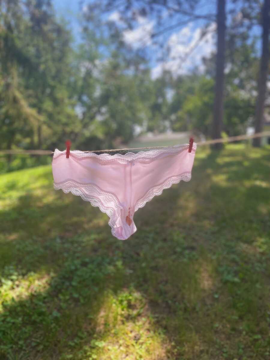 Period stained pink underwear pinned to clothesline 