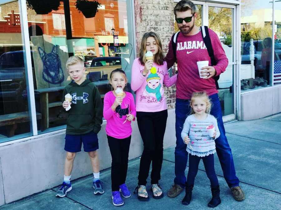 Step dad stands and eats ice cream with his stepchildren 