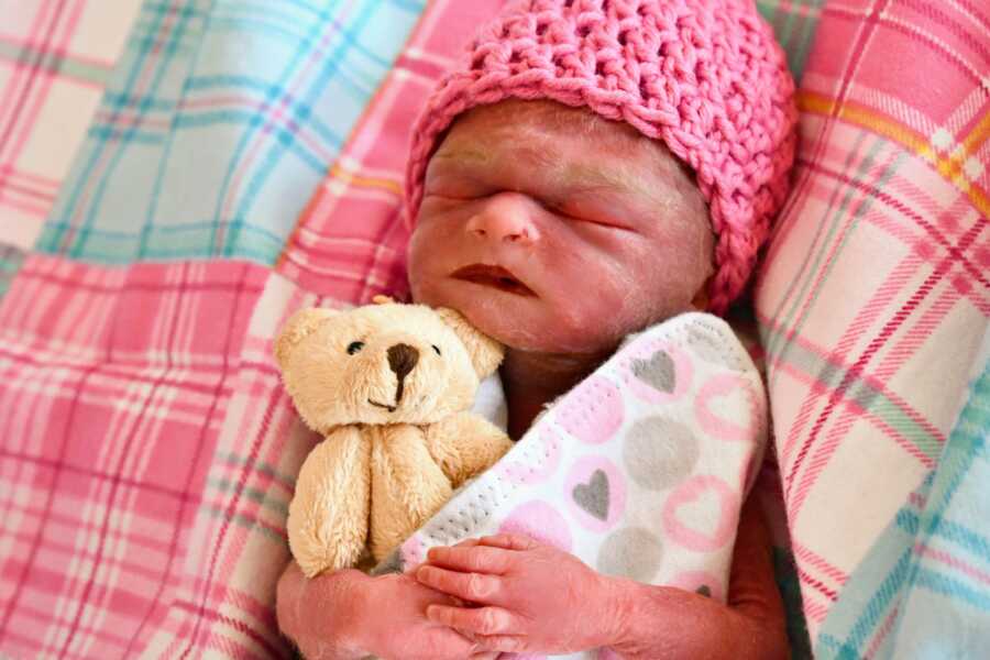stillborn daughter swaddled in blanket and wearing a pink hat