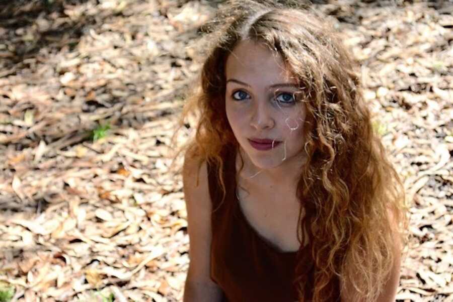 high school teenage girl sitting on woodchips