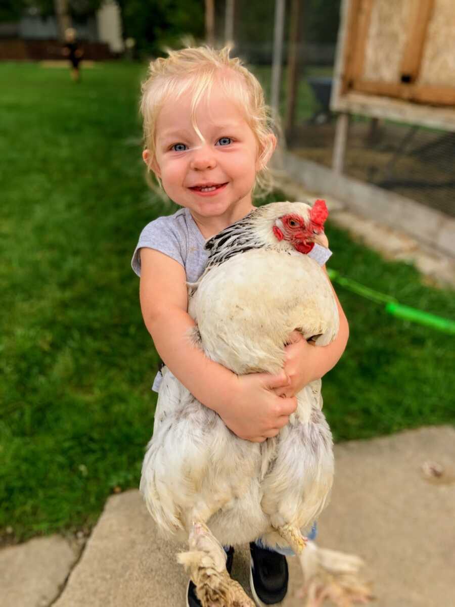 toddler daughter holding white chicken