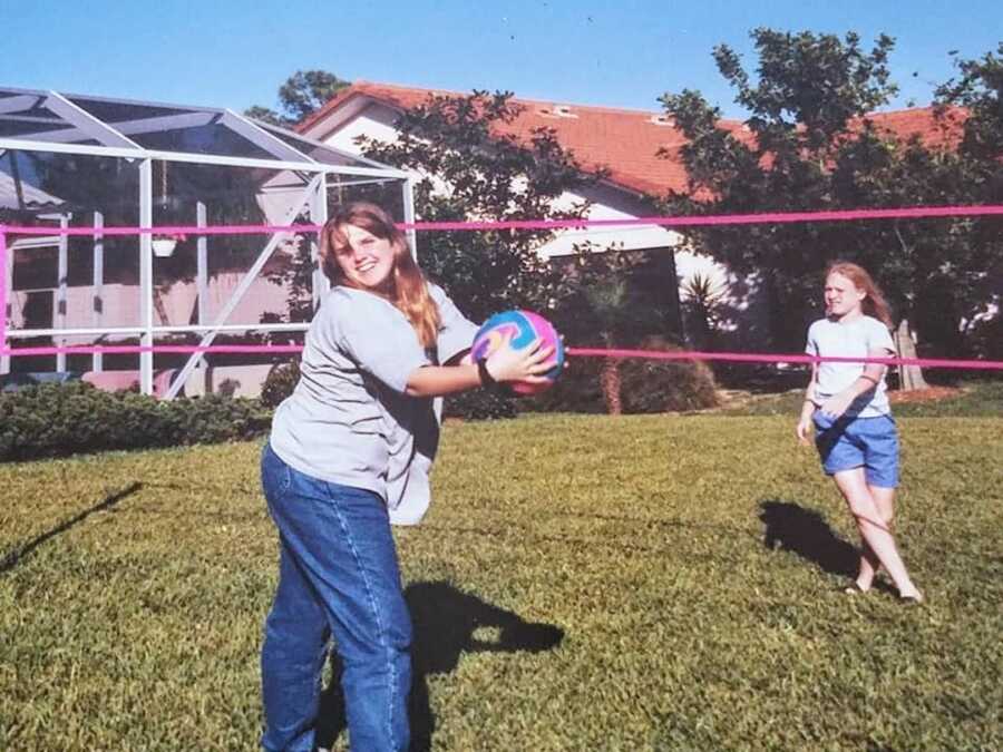 two teenage girls playing volleyball in backyard