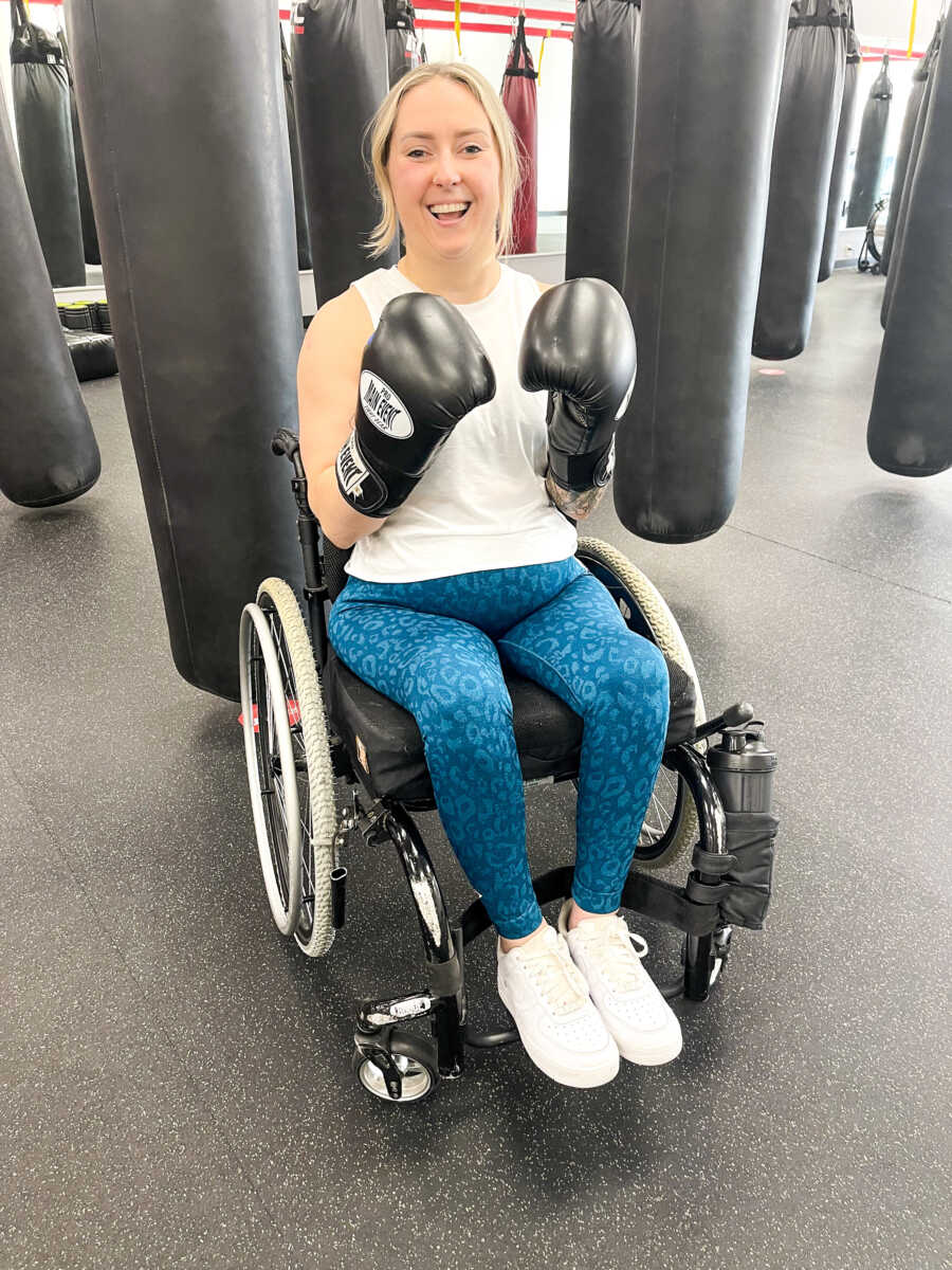 Wheelchair user sits with boxing gloves on