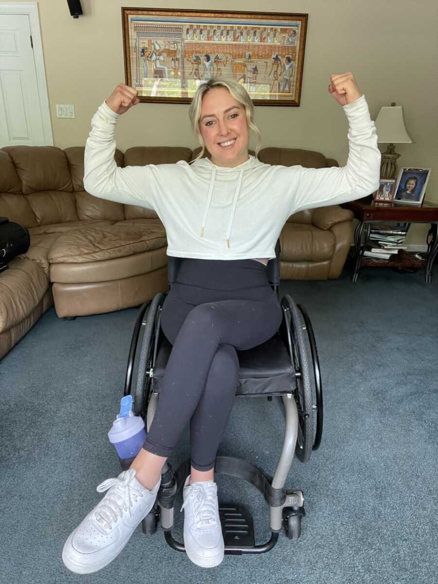 Wheelchair user flexes her arms in her living room