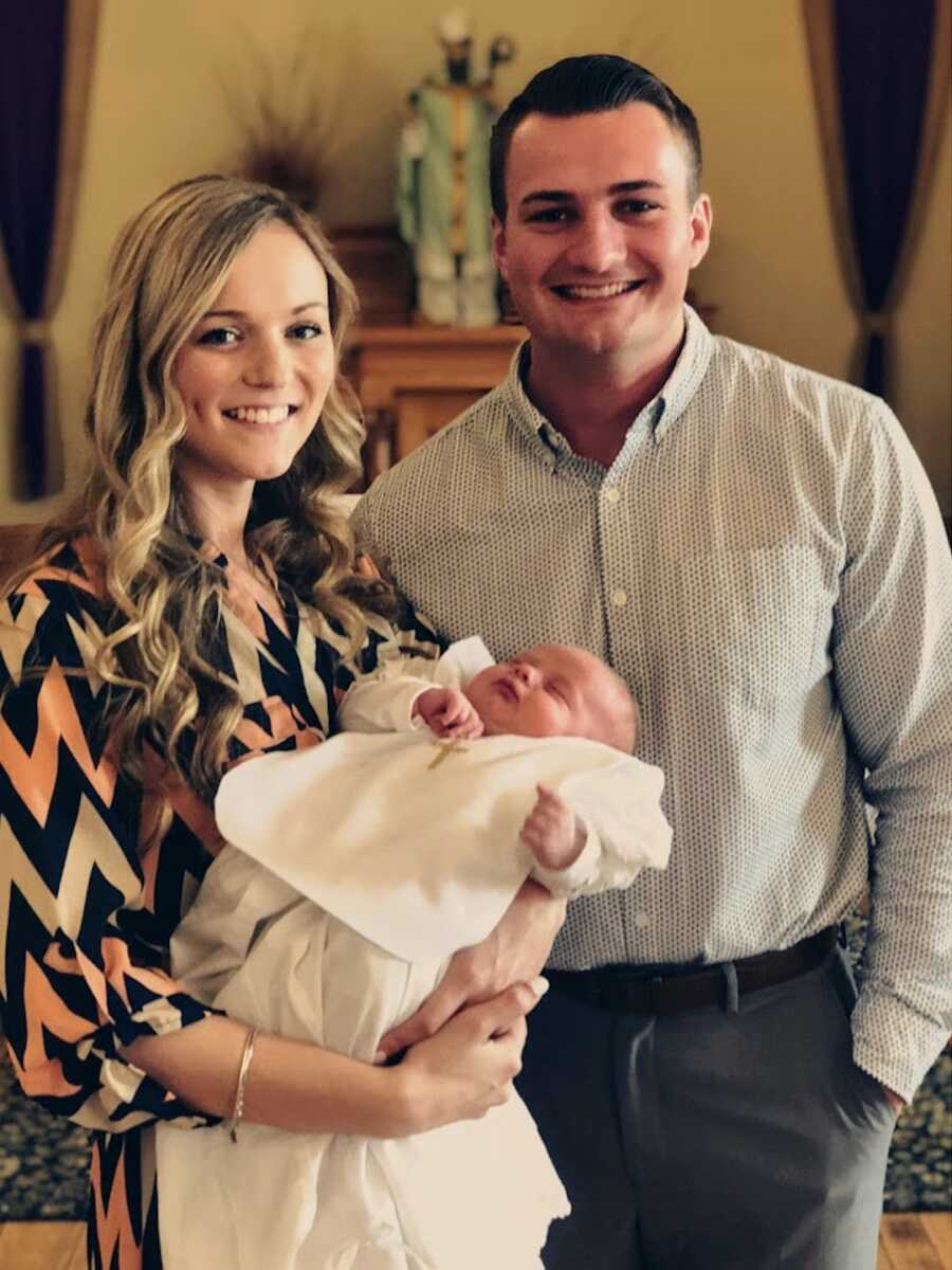 wife holding baby at her baptism with her husband