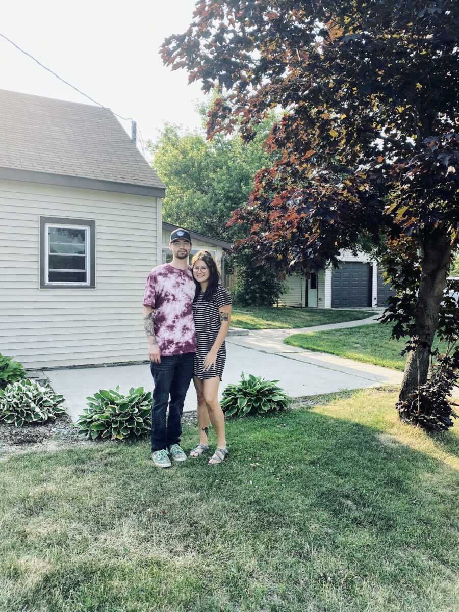 husband and wife standing in front of new home