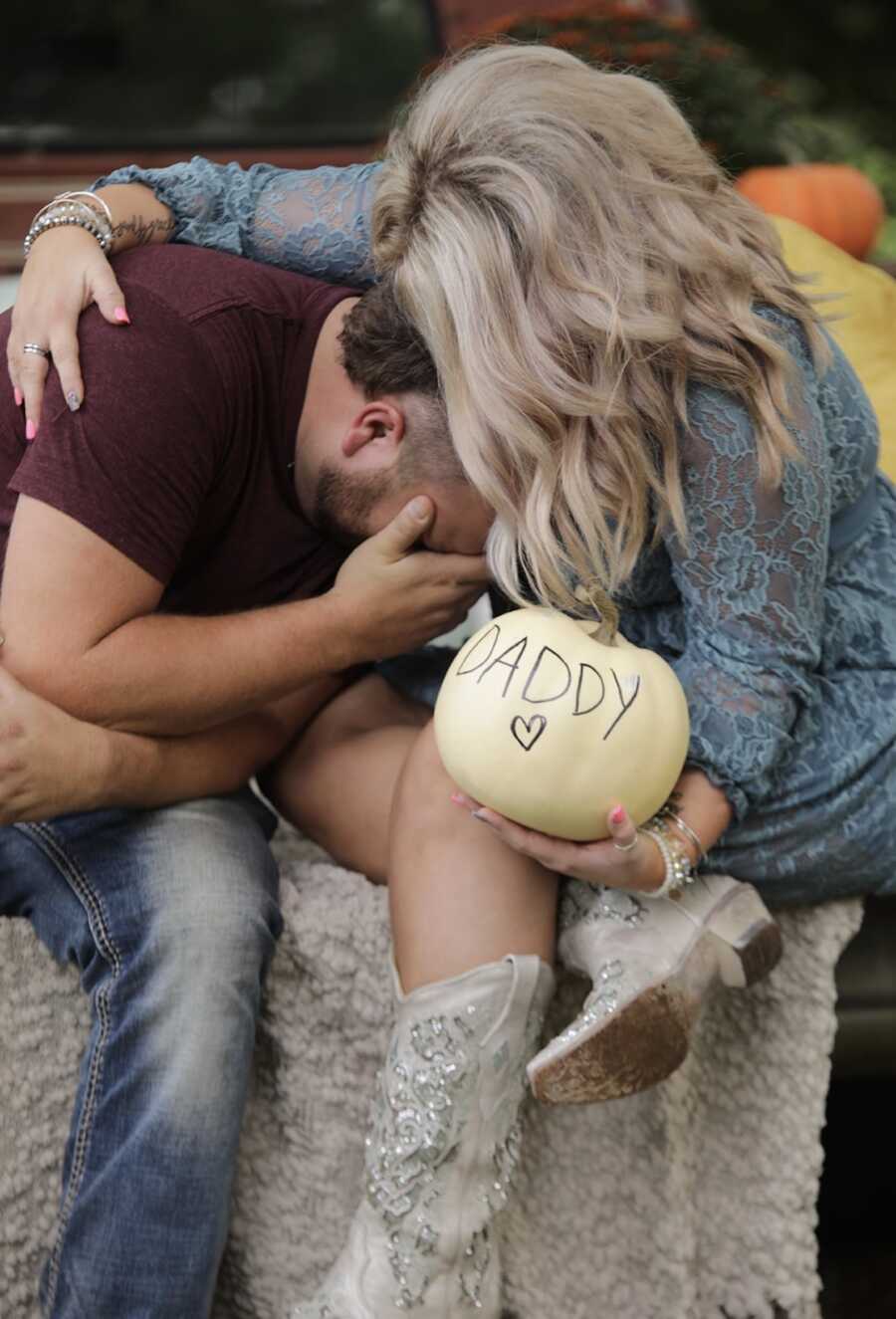 wife holds husband and pumpkin saying "DADDY"