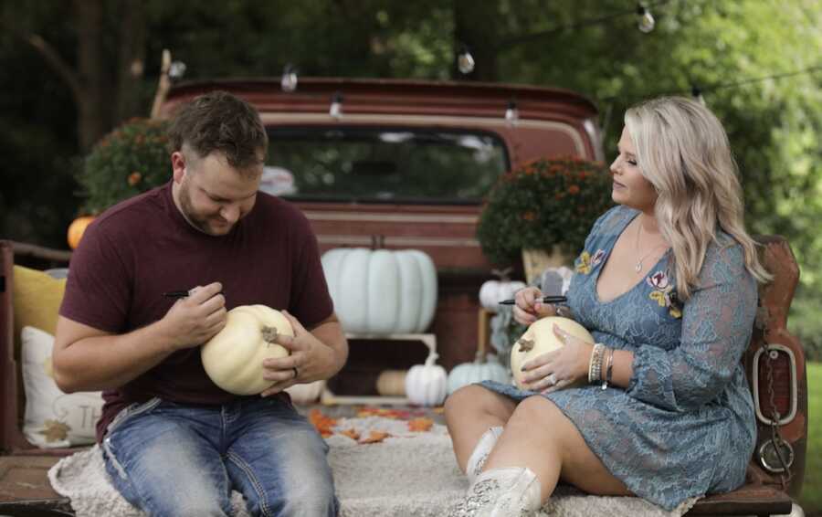 husband and wife writing on pumpkins