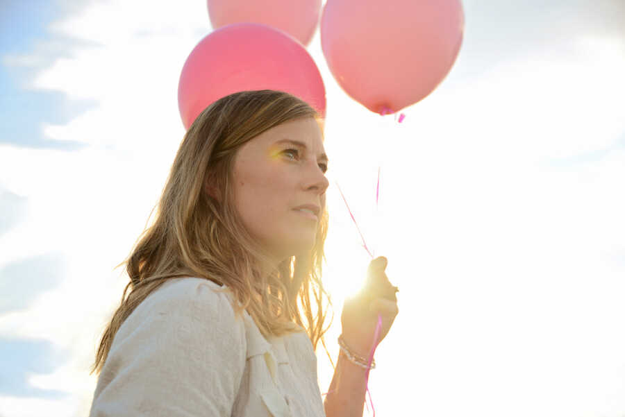 woman holding pink balloons