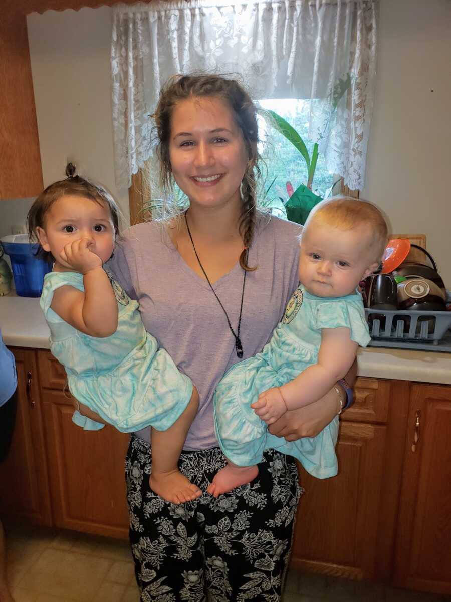 woman holding two female toddlers