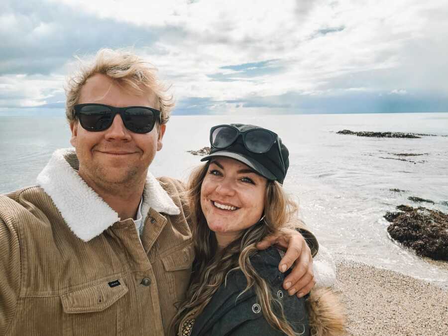 woman and partner standing by overlook off ocean