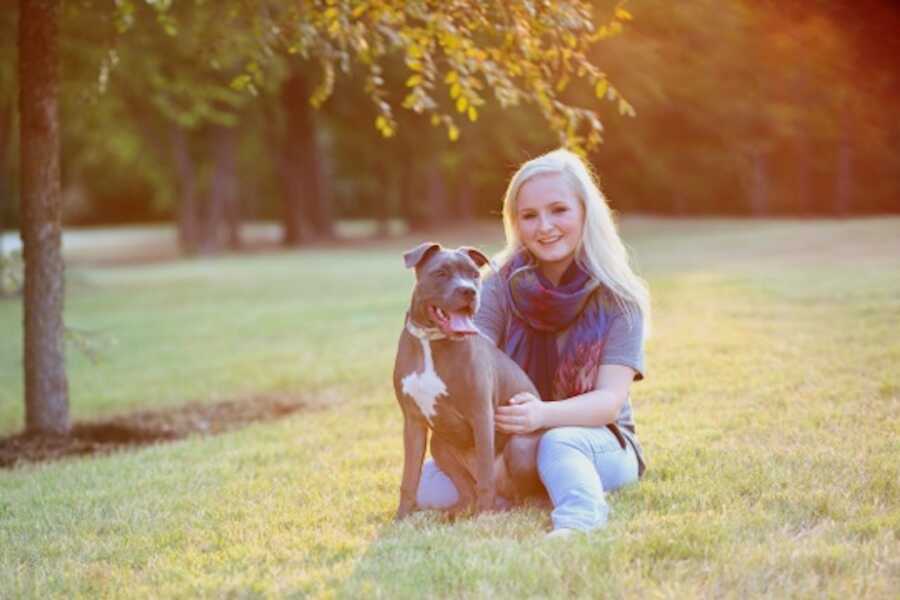 woman sitting in the grass with her dog