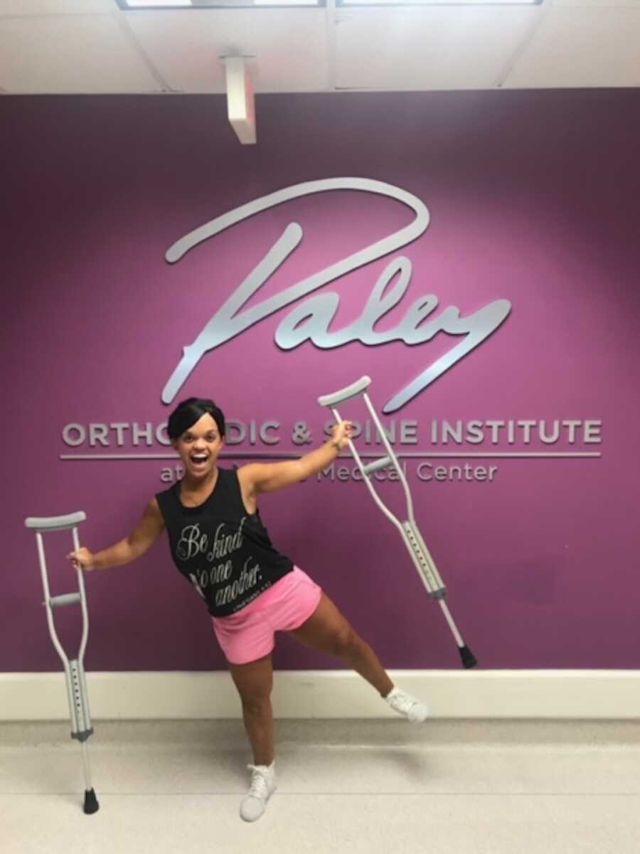 woman with dwarfism holds crutches while at medical center