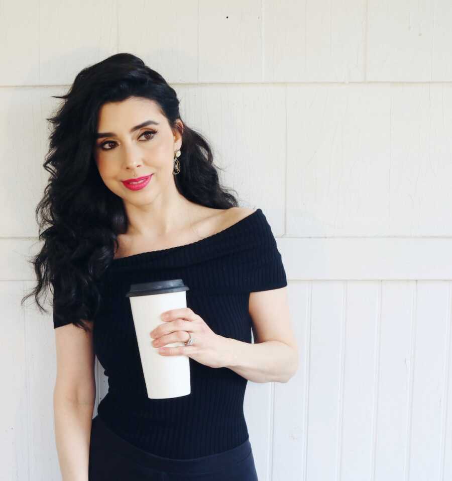 woman with lupus stands looking to distance with coffee cup