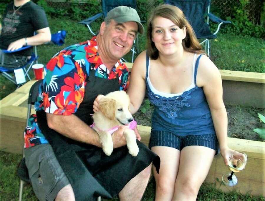 grieving daughter sitting next to her father and their puppy at a family barbeque