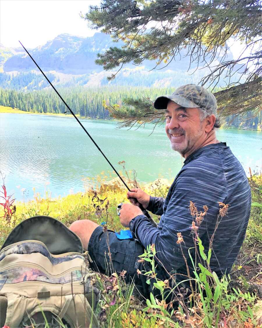 Father battling Aneurysm fishing at a lake with mountains in the background 