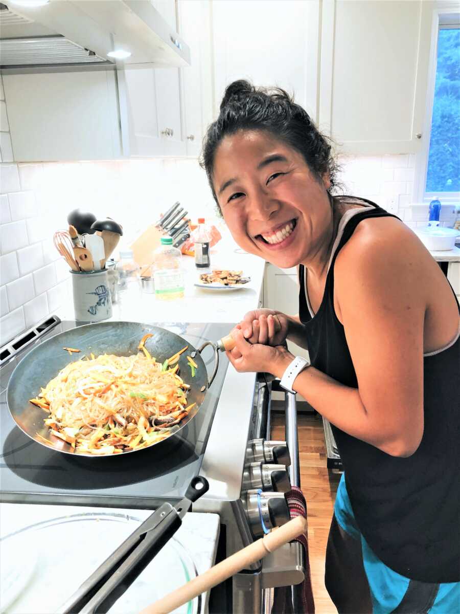 Korean adoptee cooking Korean noodles on a wok 