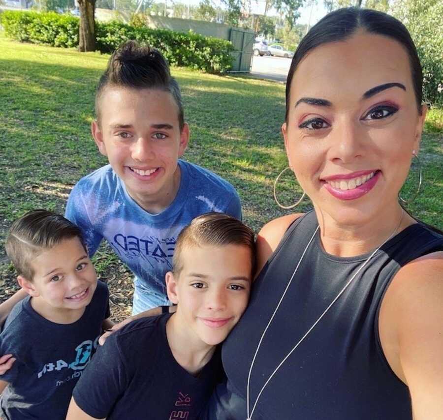 abuse survivor and mother stands with her three sons smiling
