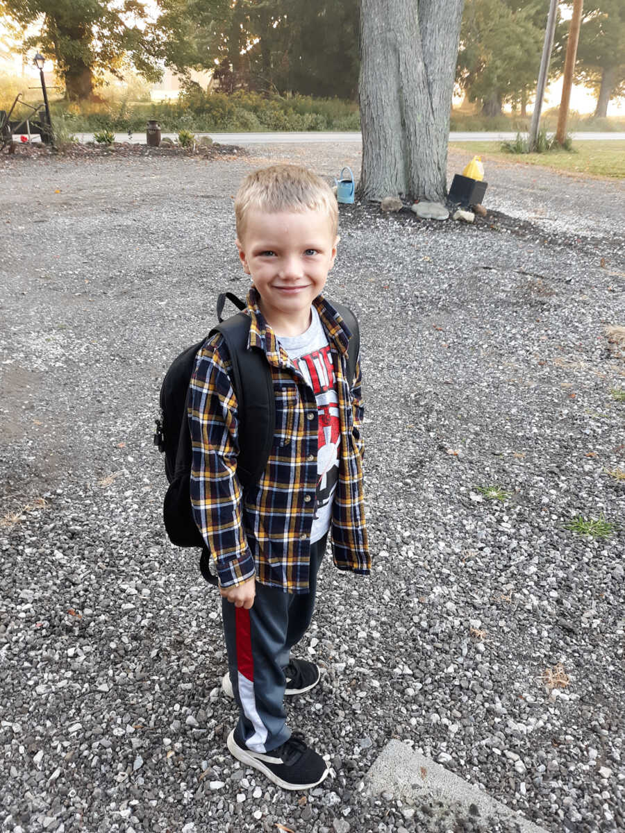 adopted boy stands while wearing a backpack