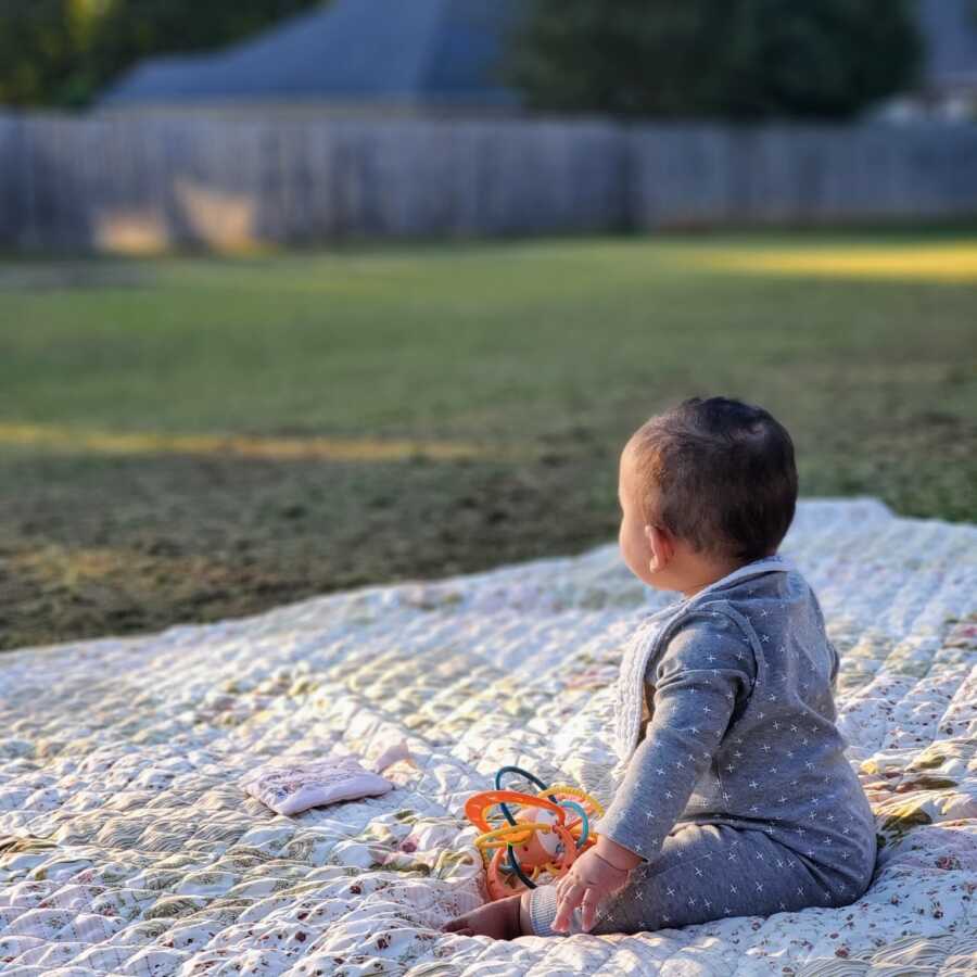 adopted son sitting on a picnic blanket outside