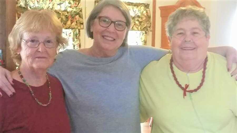 adult adoptee puts arms around half sisters