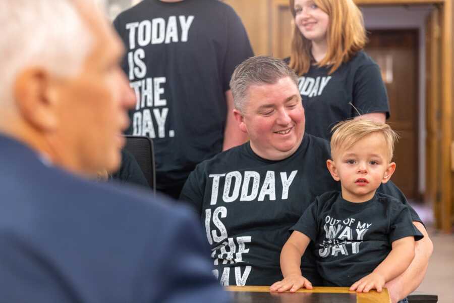 adoptive dad holds son on his lap