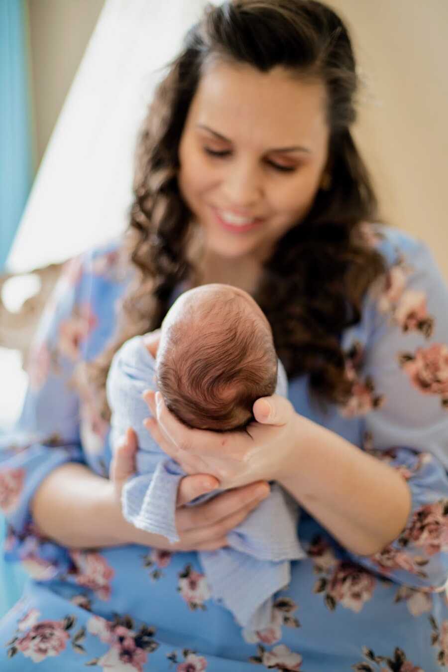 adopted mother holding her son in front of her and smiling