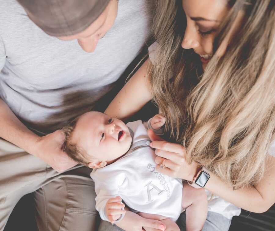 young couple lovingly hold adopted newborn