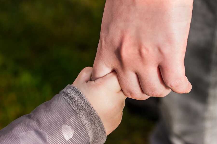 baby hand reaching up to hold adult's finger