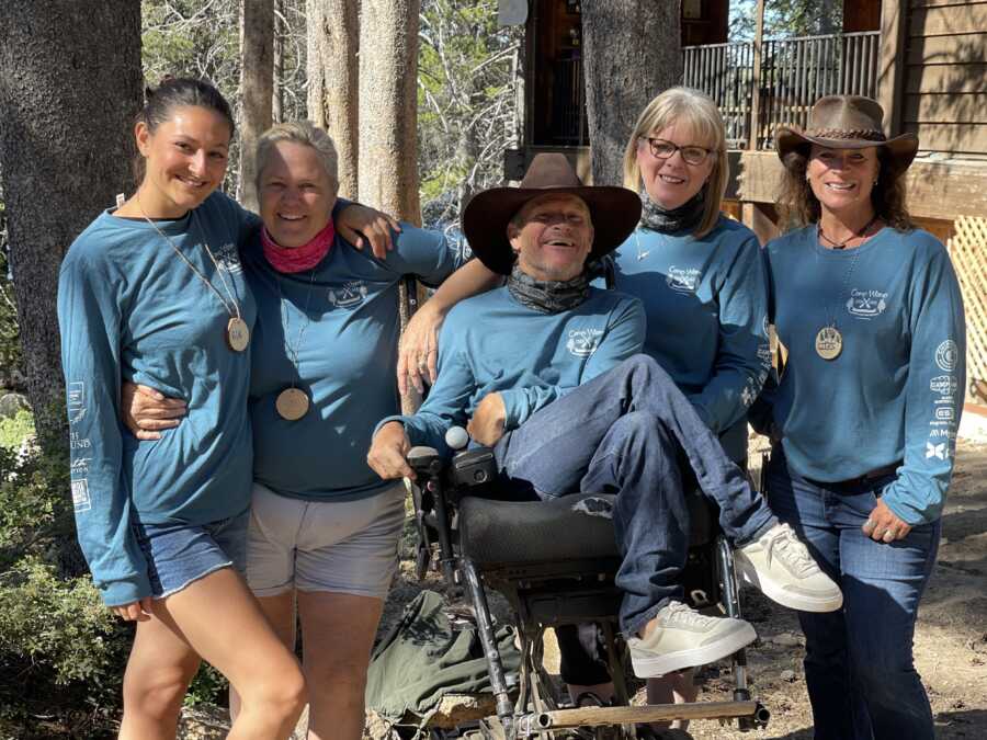 Man with cerebral palsy stands with camp staff