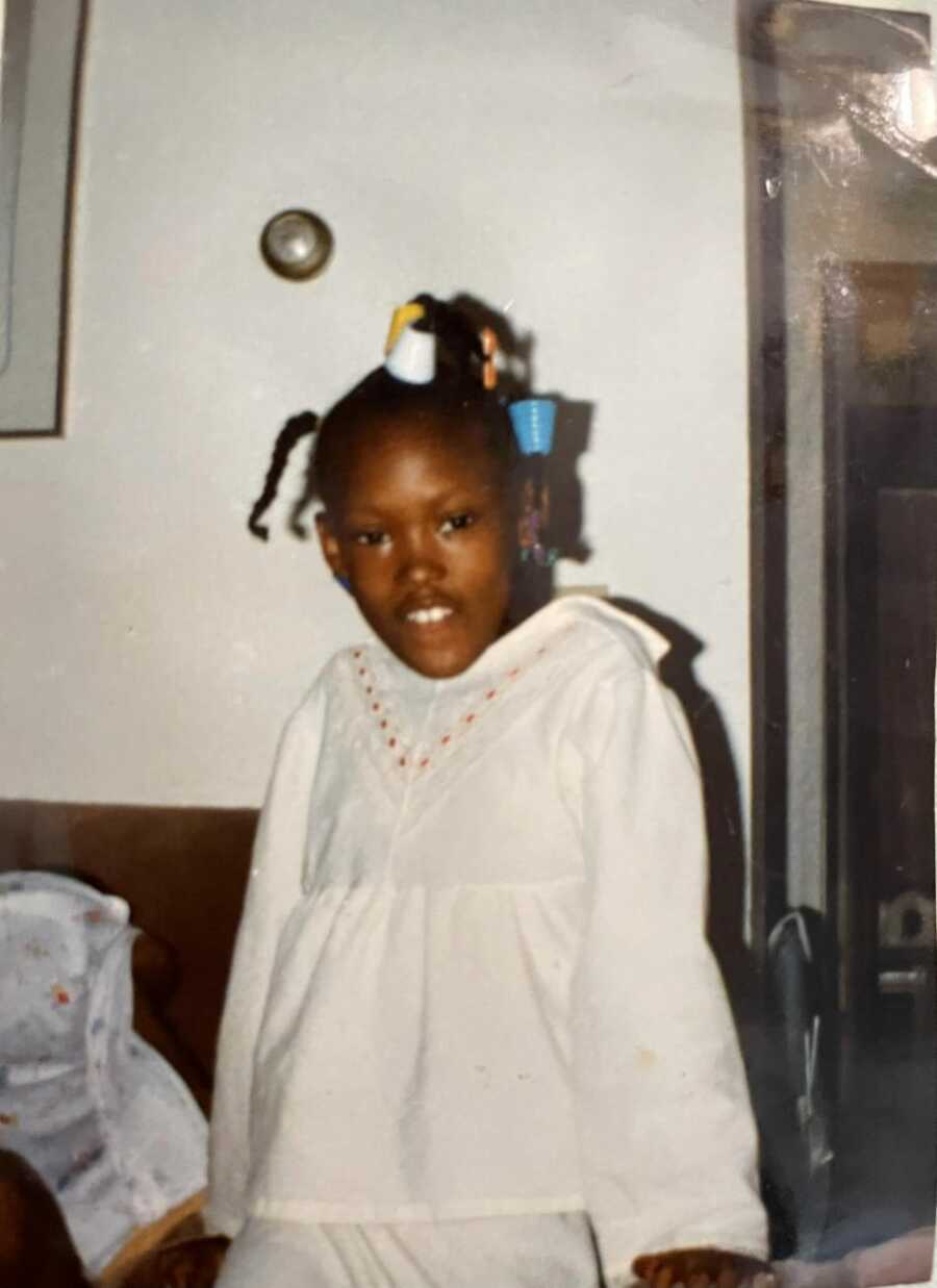 Black child wearing a white dress with colorful hair barrettes