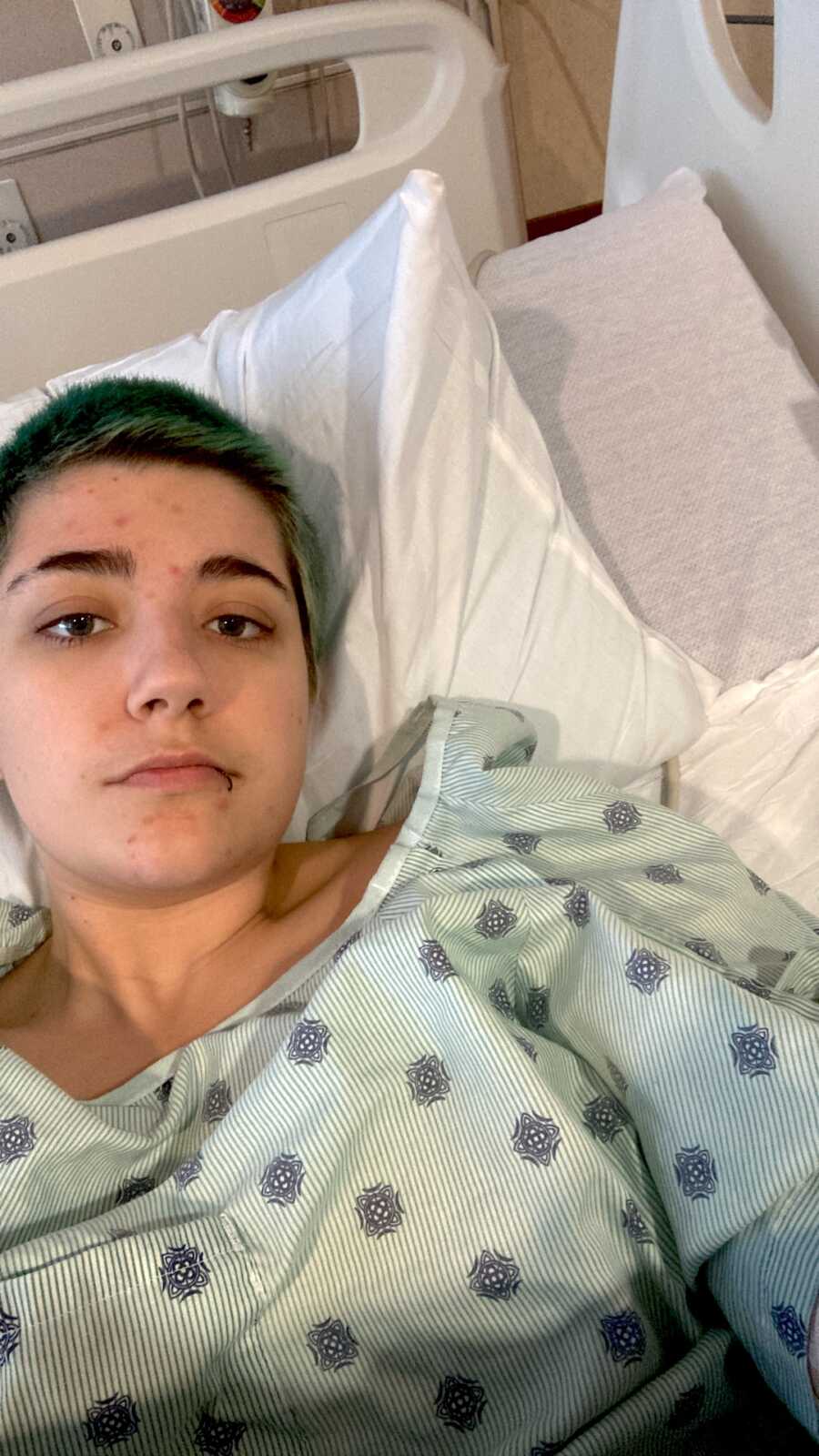 chronic illness warrior laying in hospital bed in hospital gown