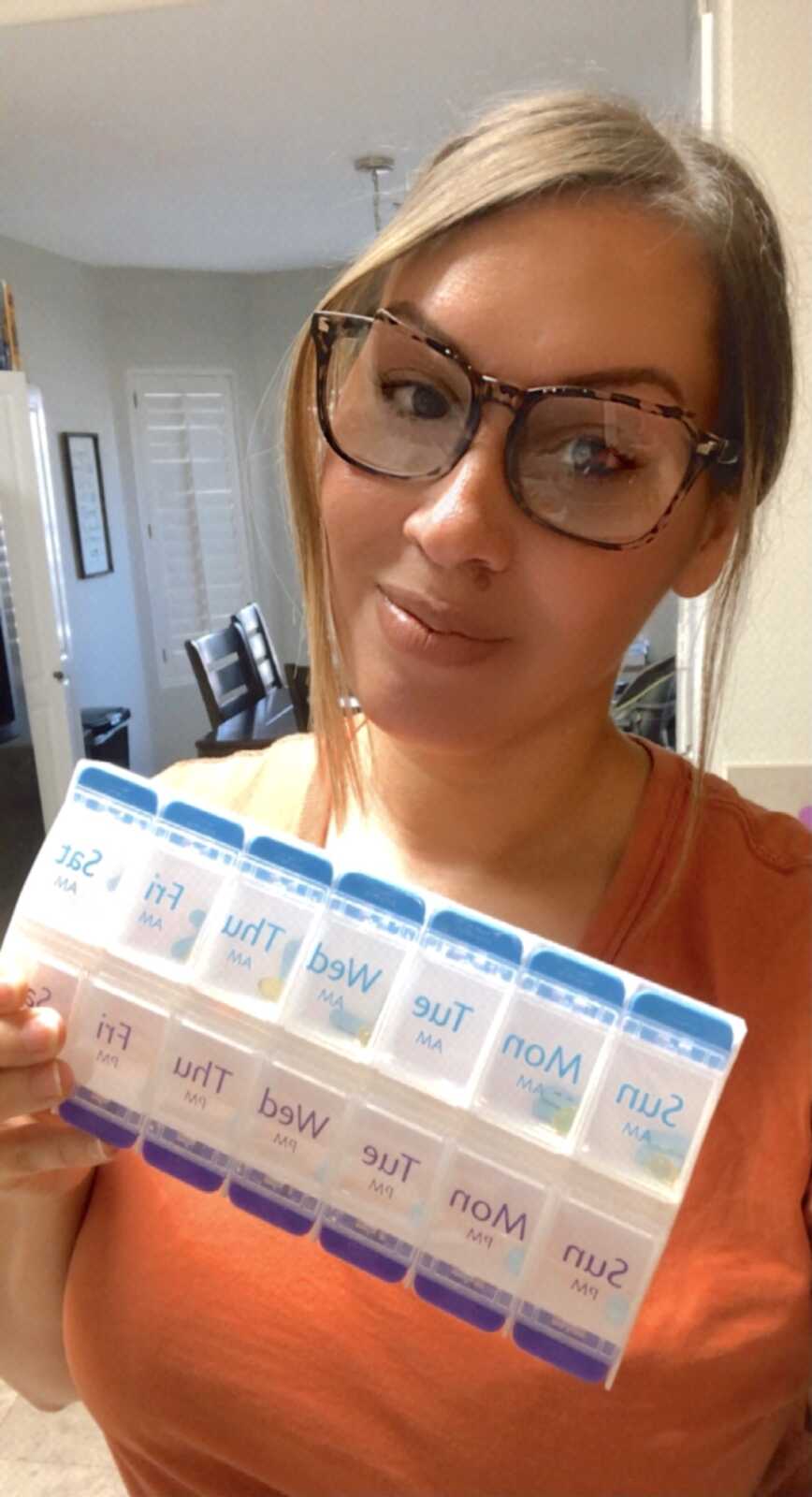 woman with chronic illness takes selfie while holding pill box